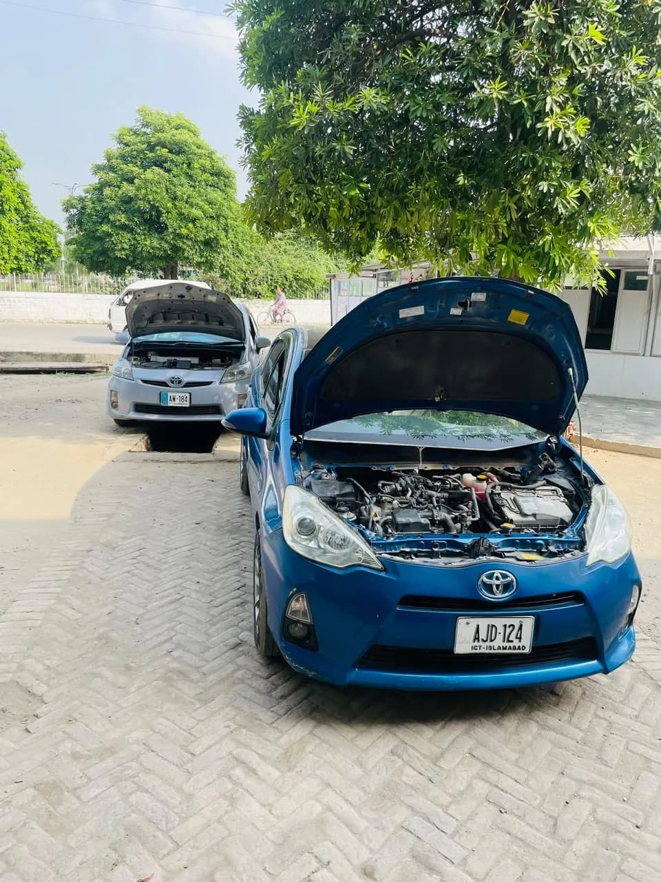 Blue Toyota Aqua hybrid with its bonnet open during a service