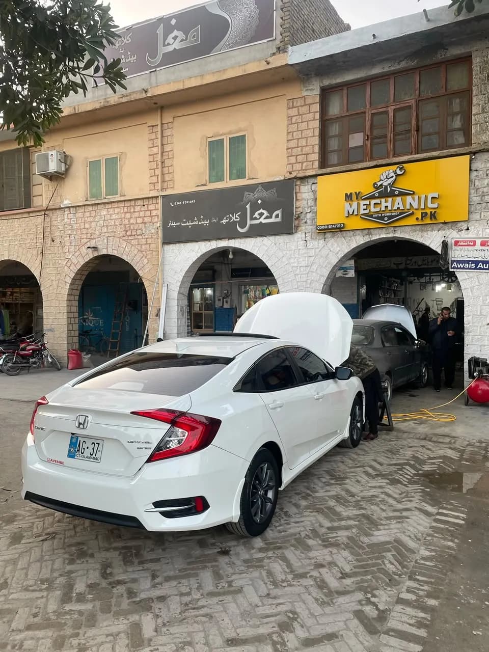 White Honda Civic with its bonnet open outside the My Mechanic workshop
